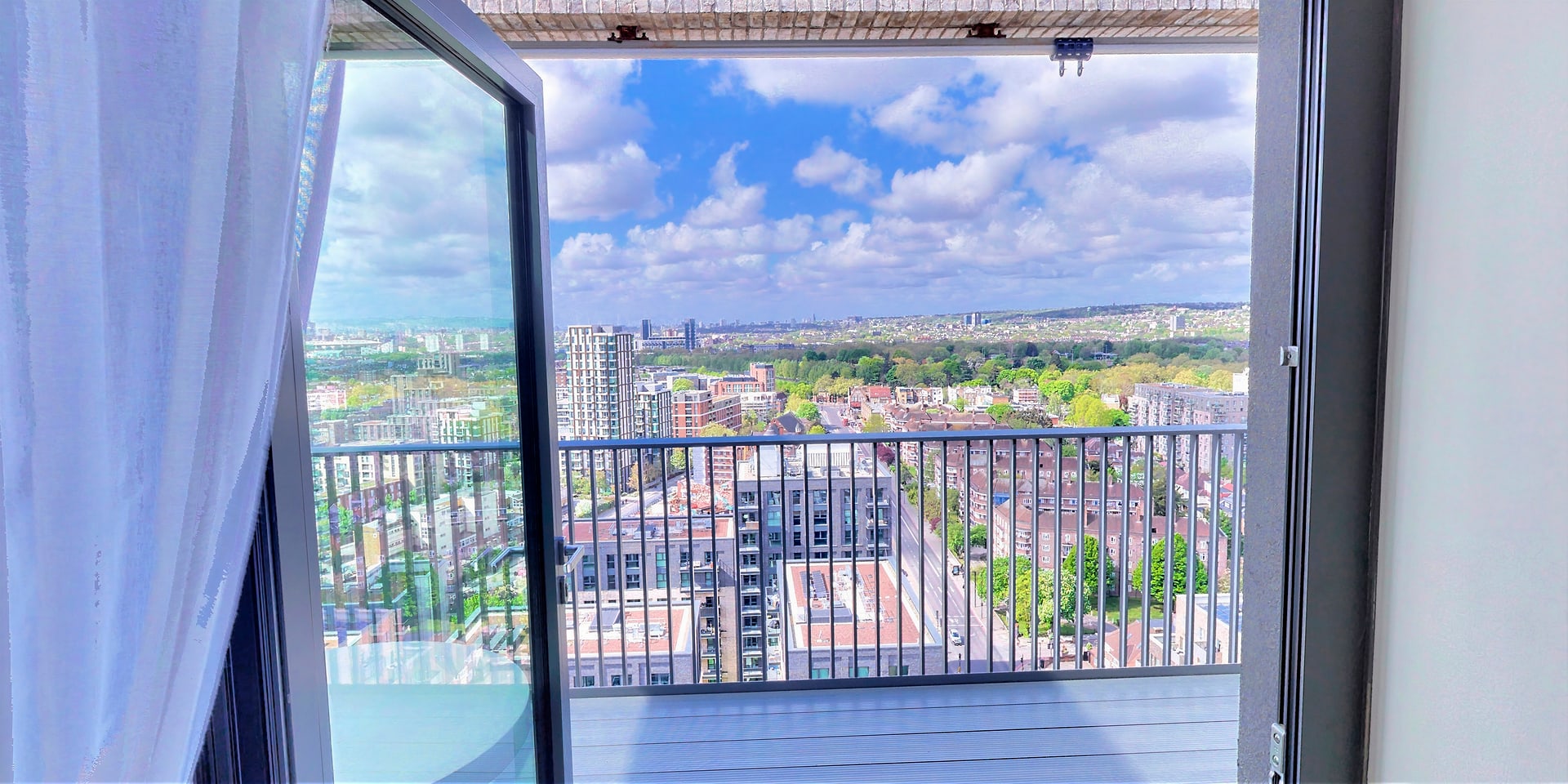 View through open glass doors onto the terrace, with the city skyline beyond