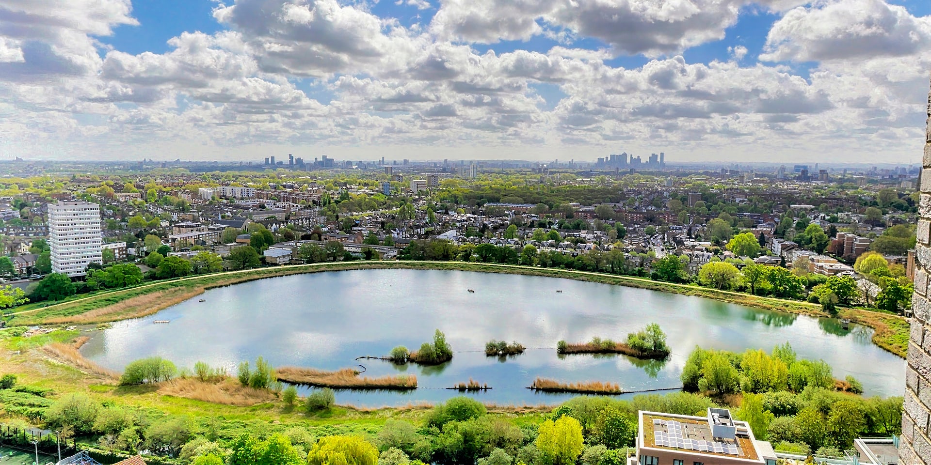 Aerial view of the 42-acre Woodberry reservoir with the London skyline beyond